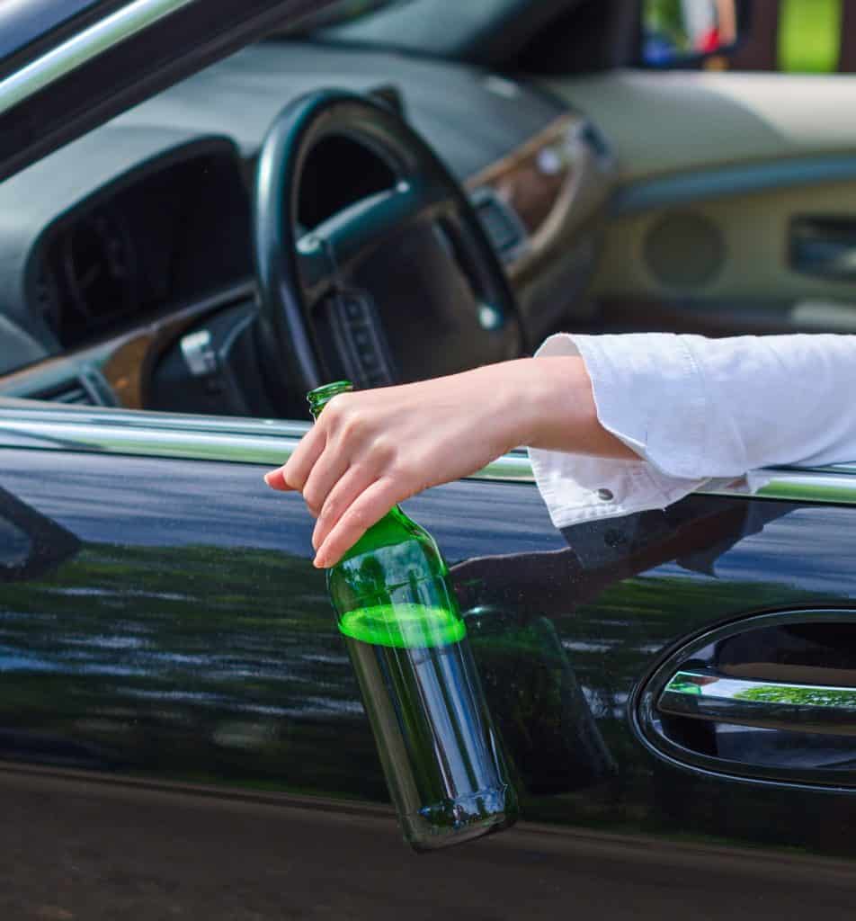 Driving Under the Influence. Female hand with bottle of beer.