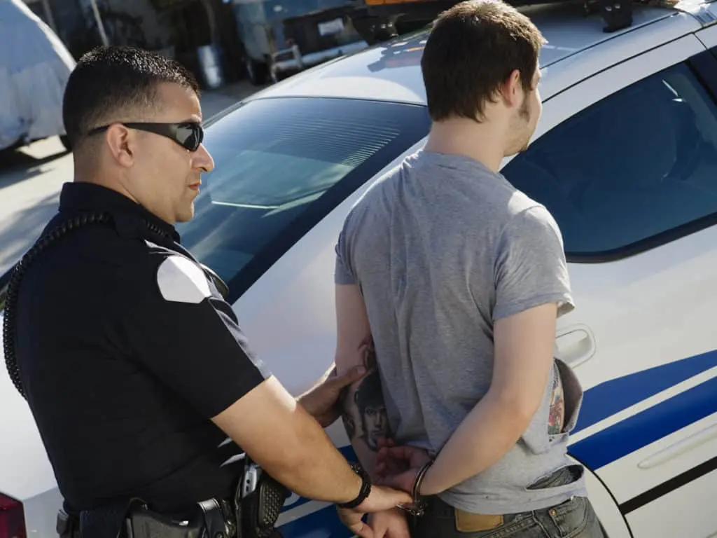 two men standing next to each other near a police car.